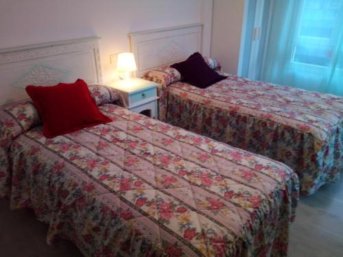 two beds in a hotel room with a red pillow at Bnap Masip in Oviedo