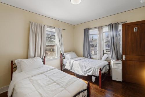 a bedroom with two beds and two windows at College Area 3BR in Grand Rapids