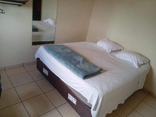 a bed in a room with white sheets and pillows at Restaurante e Hotel Campos in Nova Andradina
