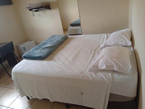 a bed with white sheets and pillows in a room at Restaurante e Hotel Campos in Nova Andradina
