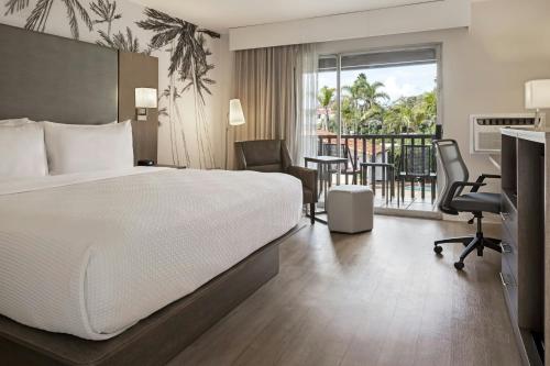 a hotel room with a bed and a desk and a balcony at FOUND Hotels, Santa Barbara, Series by Marriott in Santa Barbara