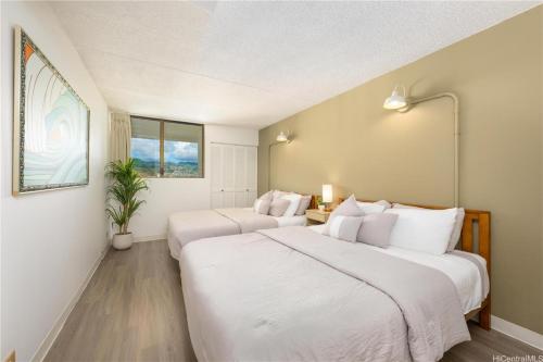 two beds in a room with white walls at Island Vacations in Honolulu