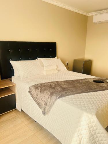 a bedroom with a large white bed with a black headboard at Rainow guest house in Burgersfort