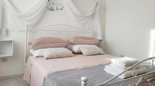 a white bedroom with a bed with pink sheets and pillows at villa mina con vasca idromassaggio in Taranto