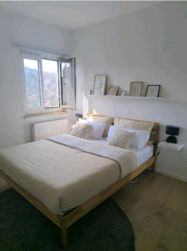 a white bedroom with a large bed with a window at Burg & Tal Panorama in Riedenburg