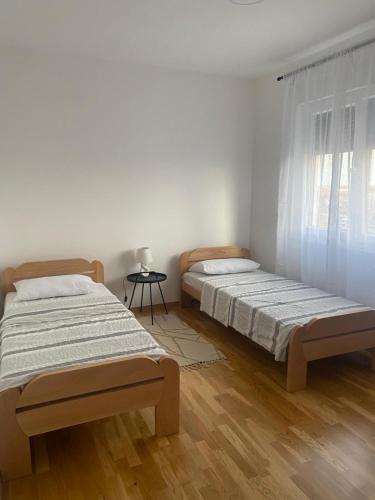two beds in a white room with a window at Apartman Park in Stara Pazova