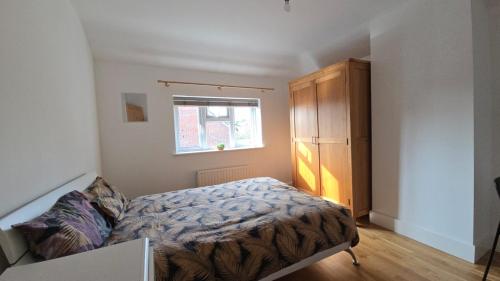 a bedroom with a bed and a wooden cabinet at Bitterne Homestay in Southampton