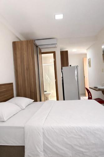 a bedroom with a white bed and a refrigerator at Boulevard Plaza Flat Mirante Apto 201 in Campina Grande