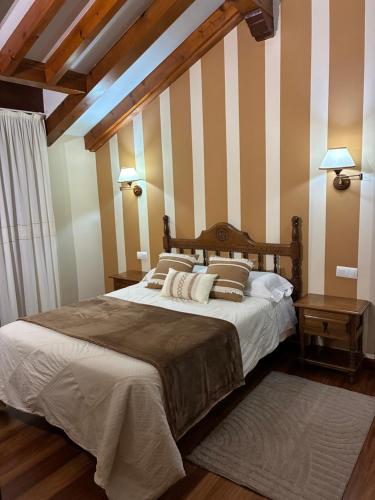 a bedroom with a large bed with striped walls at Posada El Jardin in Santillana del Mar
