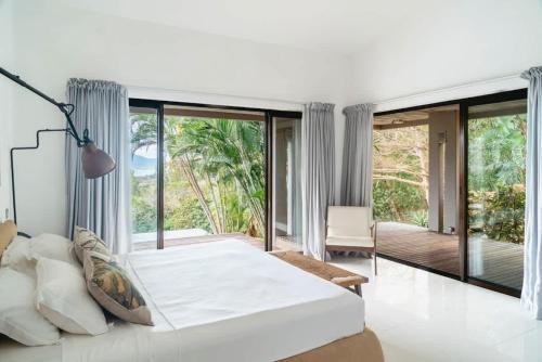 a bedroom with a large white bed and a balcony at Villa Baki - Luxe & Ocean View in Le Morne