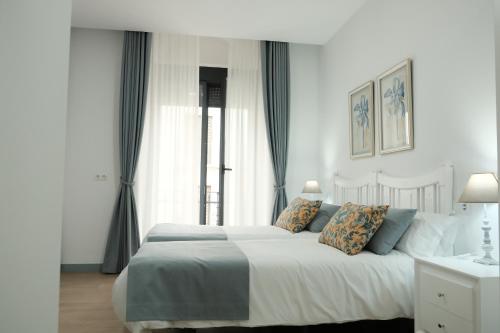 a bedroom with a large white bed with blue pillows at Balcones a San Pedro in Osuna