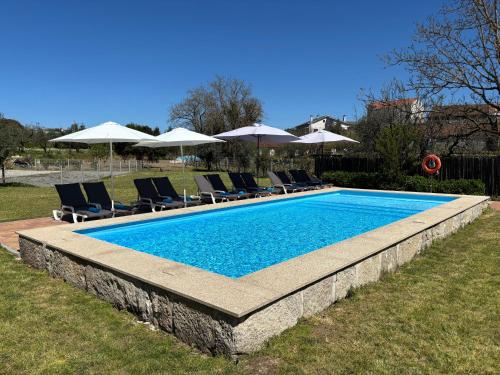 a swimming pool with chairs and umbrellas at 6 bedroom countryhouse with pool - Casa do Sepião in Vinhal