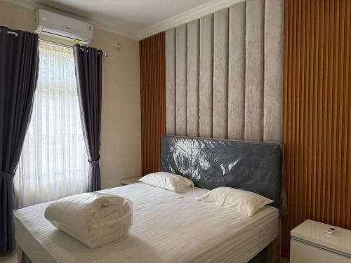 a bedroom with a bed with a headboard and a window at Eton Asia Villas-Kota Bunga in Puncak