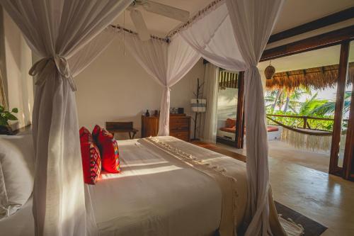 a bedroom with a white bed with red pillows at The Beach Tulum Hotel in Tulum