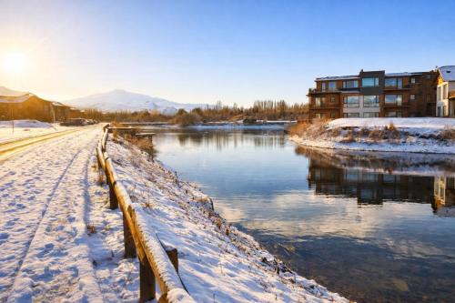 a river with snow on the ground next to a building at Blue Aparts Dina Huapi Bariloche in Dina Huapi
