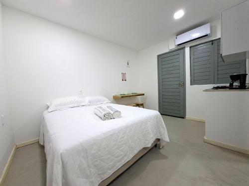 a bedroom with a white bed and a green door at Recanto de Boipeba in Ilha de Boipeba