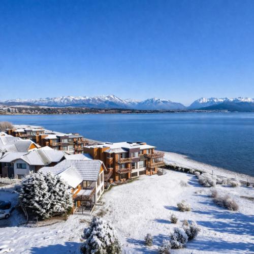 a resort on the shore of a lake with snow covered buildings at Blue Aparts Dina Huapi Bariloche in Dina Huapi