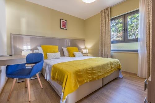 a bedroom with a bed with a desk and a blue chair at Villa REANA in Brela