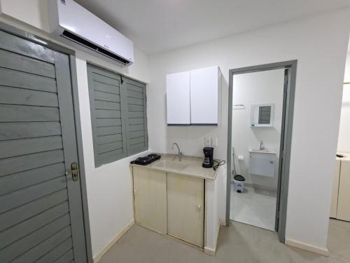 a white kitchen with a sink and a bathroom at Recanto de Boipeba in Ilha de Boipeba