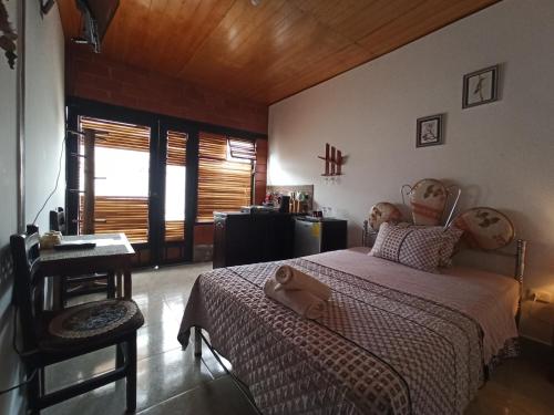 a bedroom with a bed and a table and a desk at Home Capybara Stay in Mindo