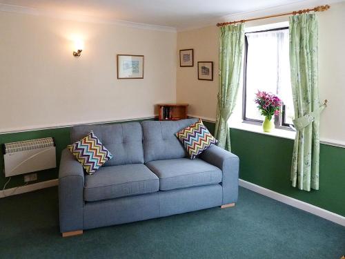 a living room with a blue couch and a window at Juniper - 28060 in Wheddon Cross
