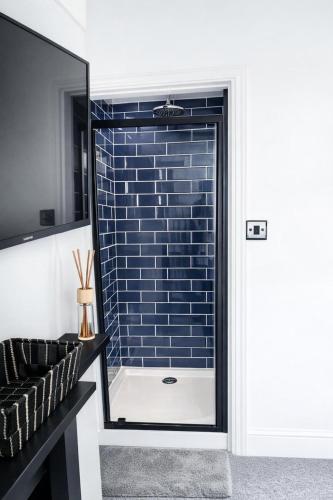a bathroom with a glass door with a brick wall at Coastal Nest in Hollington