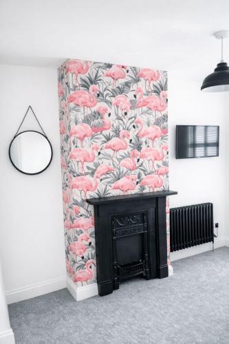 a fireplace in a room with a red flamingo wallpaper at Coastal Nest in Hollington