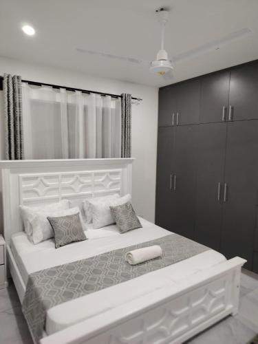 a white bedroom with a large white bed and cabinets at Nyali luxe 1 bedroom in Nyali