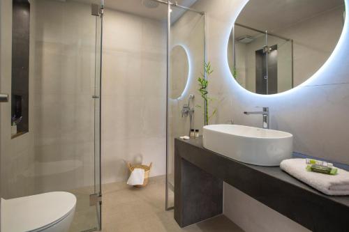 a bathroom with a sink and a toilet and a mirror at Elysian Luxury Suite in Preveza