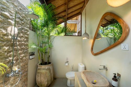 a bathroom with a shower and a toilet and a plant at Incense Impossible Beach Boutique Hotel - Adults Only in Uluwatu