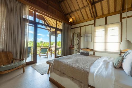 a bedroom with a large bed and a balcony at Incense Impossible Beach Boutique Hotel - Adults Only in Uluwatu