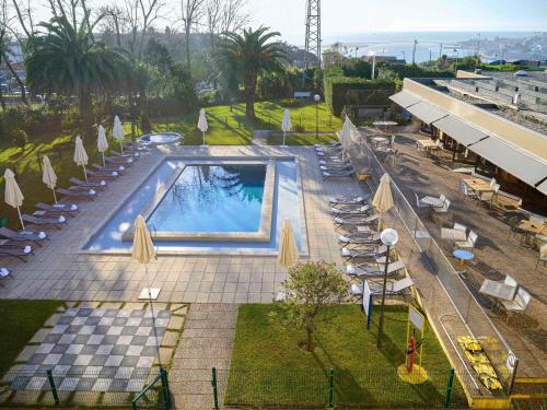 an overhead view of a swimming pool with chairs and umbrellas at Novotel Porto Gaia in Vila Nova de Gaia