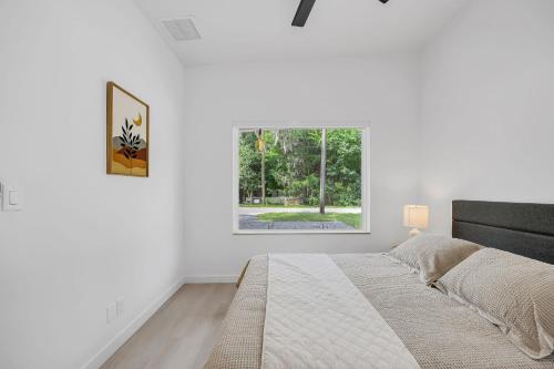 a white bedroom with a bed and a window at Ember & Oak - Modern Retreat Near Downtown - Pets in St. Augustine