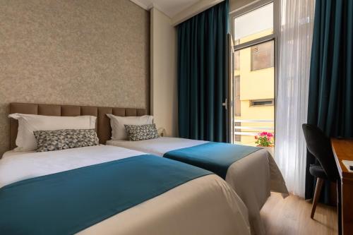 a hotel room with two beds and a window at Golden City Boutique Hotel Tirana in Tirana