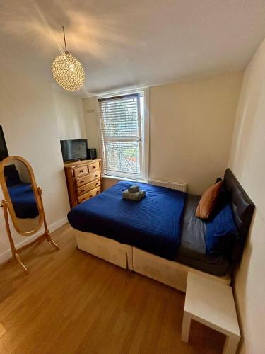 a bedroom with a bed with a blue comforter and a window at Lord's Guesthouse - Room 4 in London