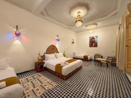 a bedroom with two beds and a table and chairs at Riad Fez Guests in Fez