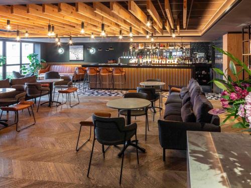a bar with couches and tables and a bar withools at Novotel Birmingham Airport Terminal Building - NEC in Bickenhill
