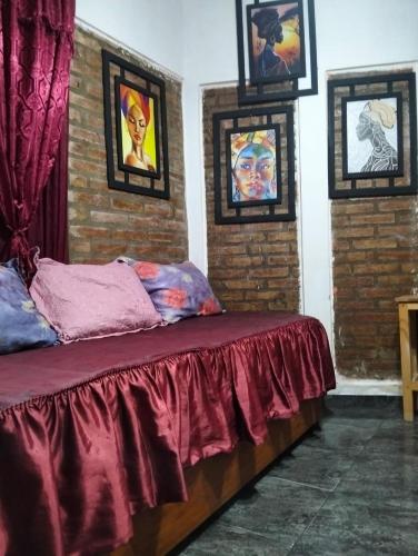 a bed in a room with paintings on the wall at Elba Cabañas in Villa Carlos Paz