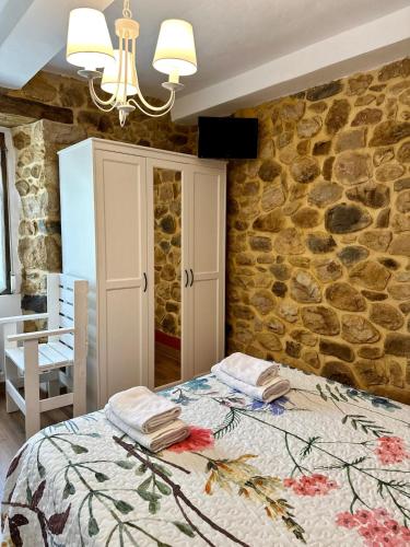 a bedroom with a bed and a stone wall at Casa La Ería in Sevares