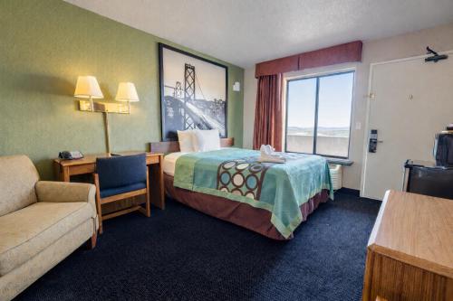a hotel room with a bed and a couch and a window at Super 8 by Wyndham Barstow in Barstow
