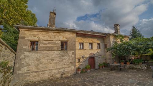 a large brick building with a table in front of it at Astraka Guesthouse I in Papigko