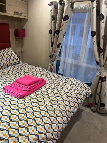 a bedroom with a bed with a pink towel on it at 3 bedroom, 2 bathroom caravan Presthaven Beach Resort in Talacre