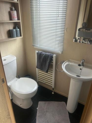 a bathroom with a white toilet and a sink at 3 bedroom, 2 bathroom caravan Presthaven Beach Resort in Talacre