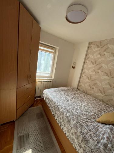 a bedroom with a bed and a cabinet and a window at ANKA apartman in Smederevo