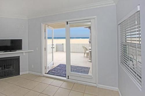 a living room with a fireplace and a sliding glass door at 8-Bedroom Beachfront Triplex – Ideal for Extended apts in Newport Beach
