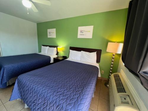 a hotel room with two beds and a flat screen tv at Hwy 59 Motel Laredo Medical Center in Laredo