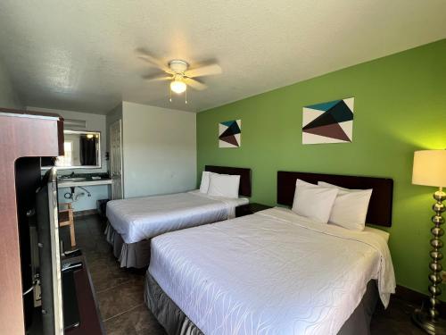 two beds in a room with green walls at Hwy 59 Motel Laredo Medical Center in Laredo