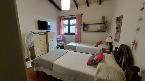 a bedroom with two beds and a dresser with a fan at Casa confortable - Parque central - Estacionamiento, patio, 3 baños, 5 habitaciones - in La Cieneguita