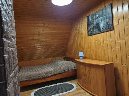 a small room with a bed in a wooden cabin at Domki Całoroczne Pod Lasem in Łobozew