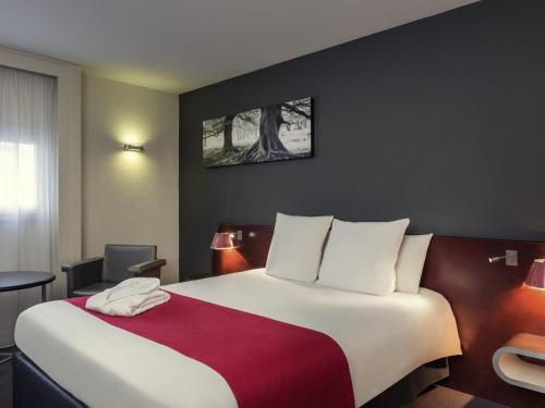 a hotel room with a large bed with a red blanket at Mercure Rennes Centre Gare in Rennes